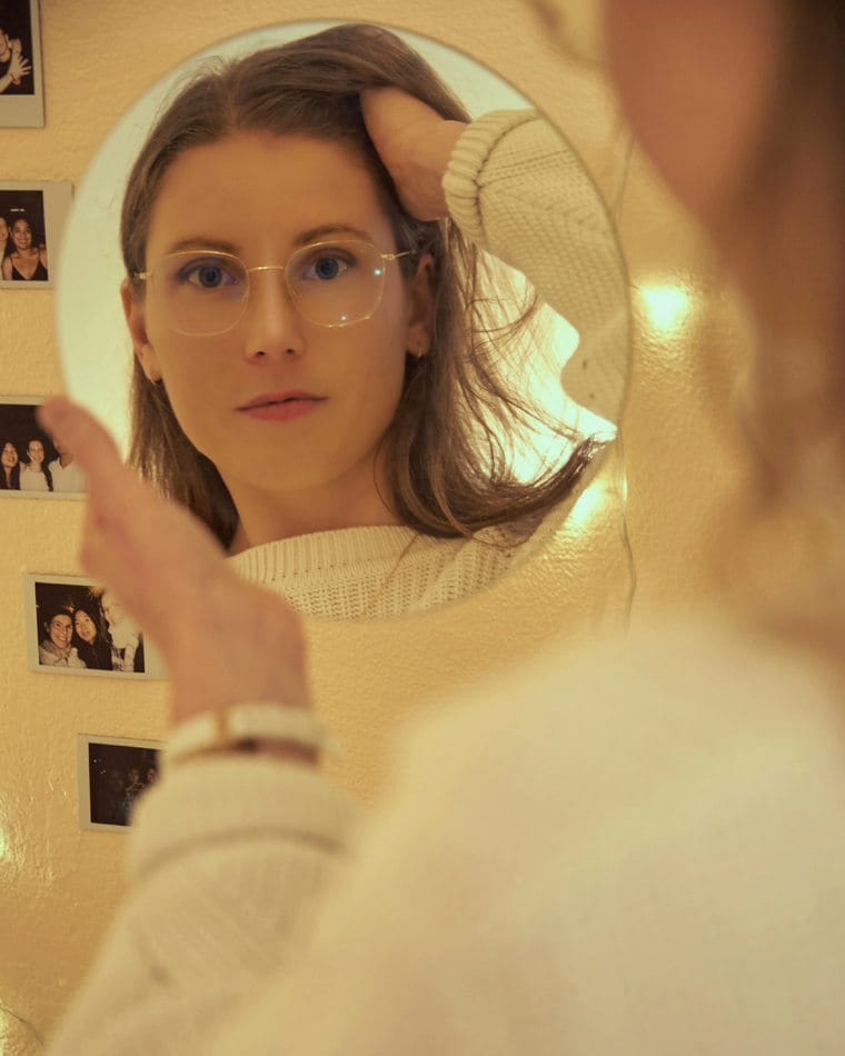 Lucie Lemaître, coach certifiée en neurodiversité, face à son miroir, entourée de photos souvenirs