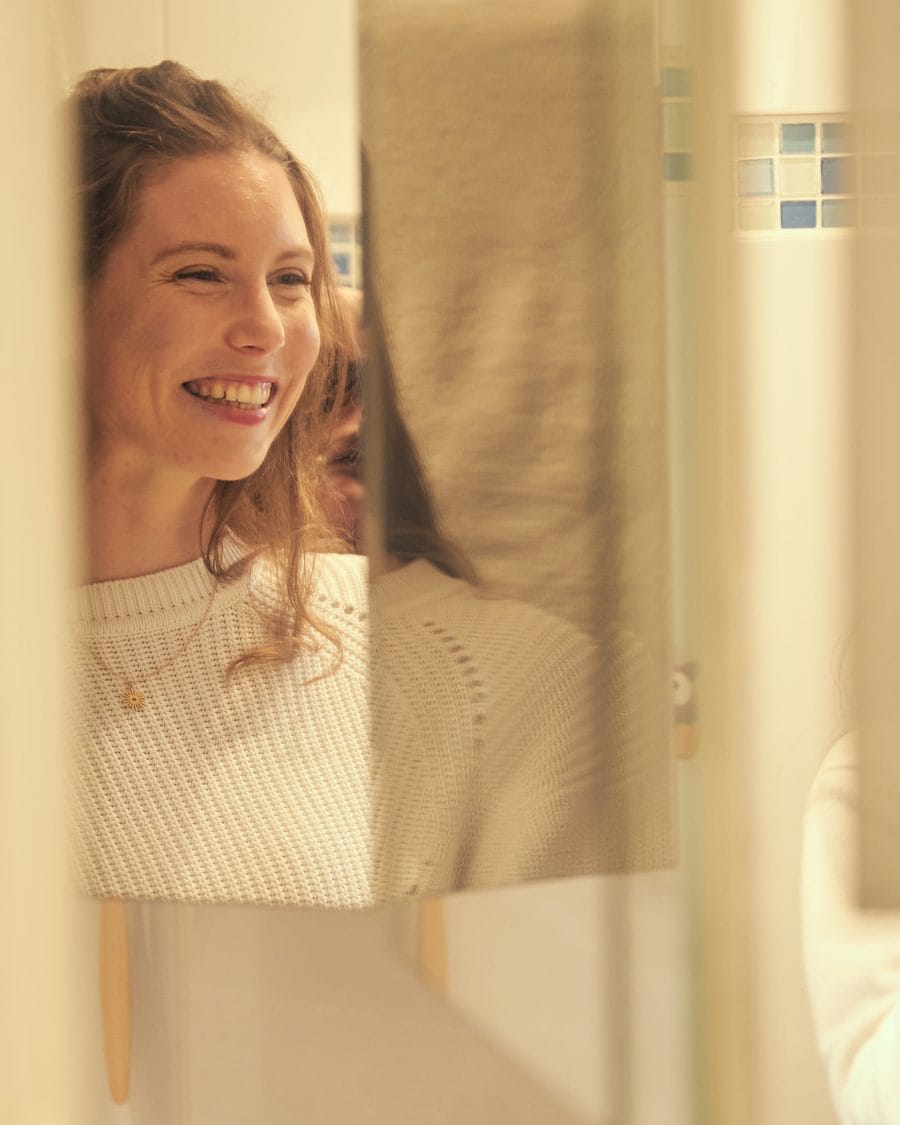 Lucie Lemaître, coach en neurodiversité, souriante face à son reflet dans le miroir